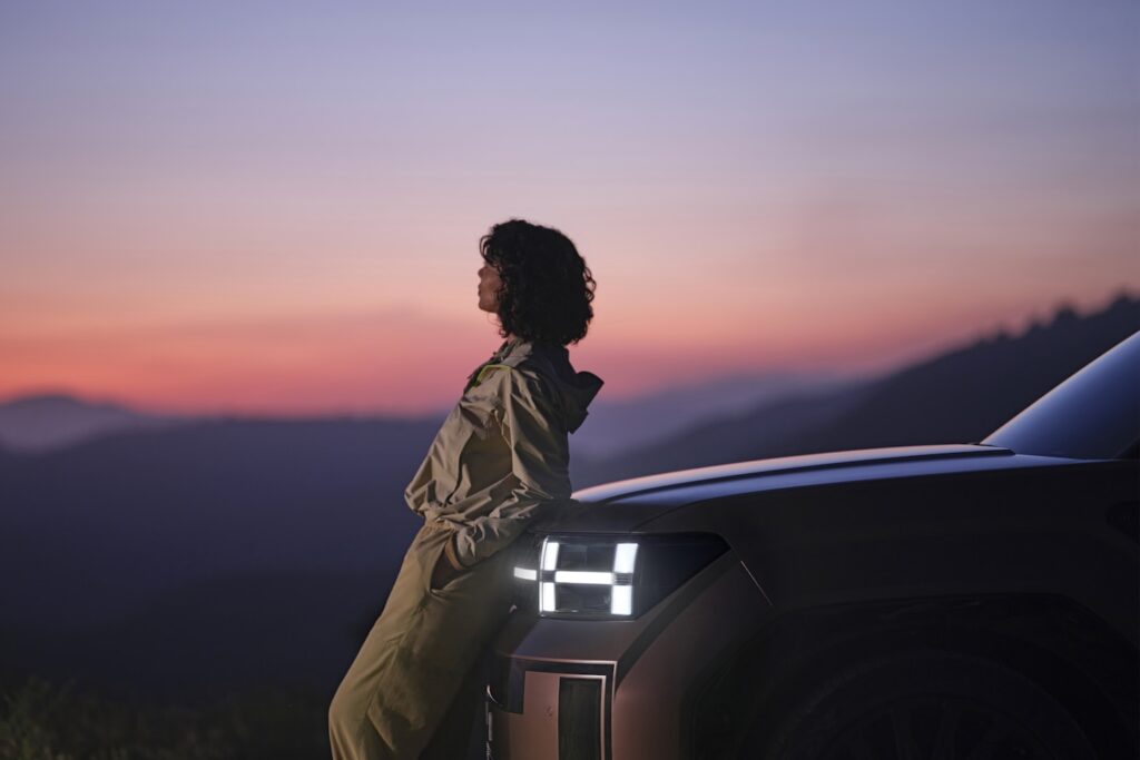 A person watching the sunset while leaning on the Hyundai SANTA FE.