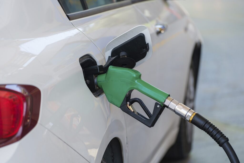 Gas pump nozzle in the fuel tank of a white car, refuel