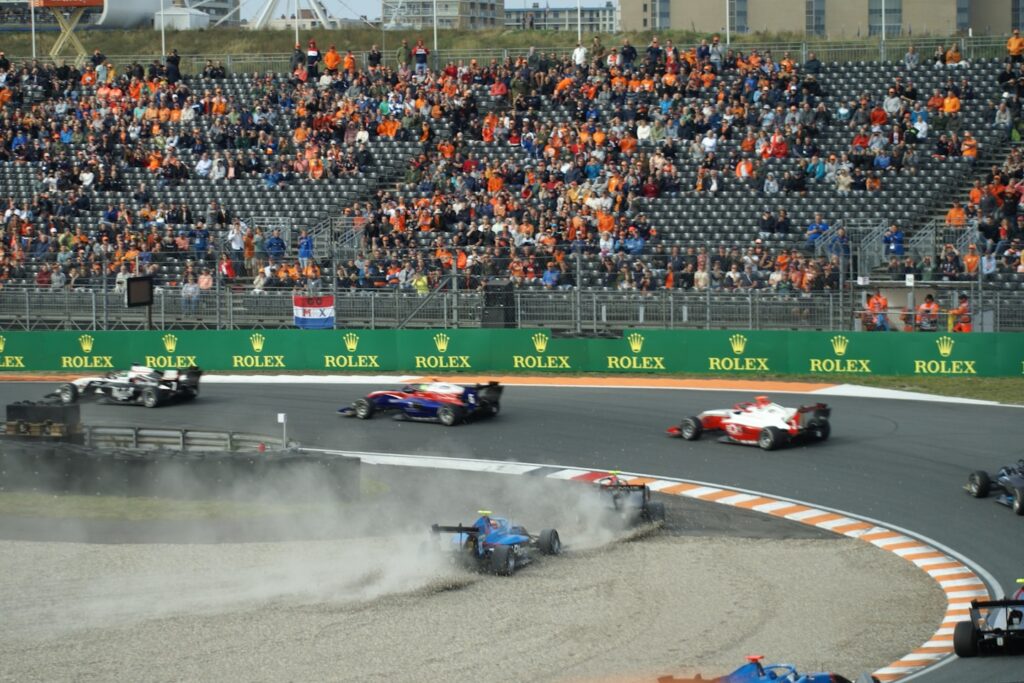 a group of race cars on a track with a crowd watching