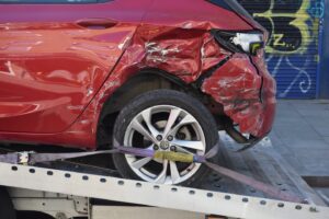 Image of a red car being towed/recovered which was involved in a road traffic collision.